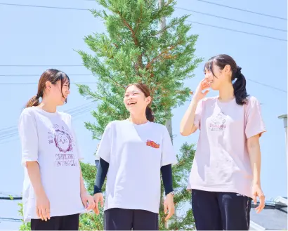 保育士3人が青空の下で笑顔で話している様子