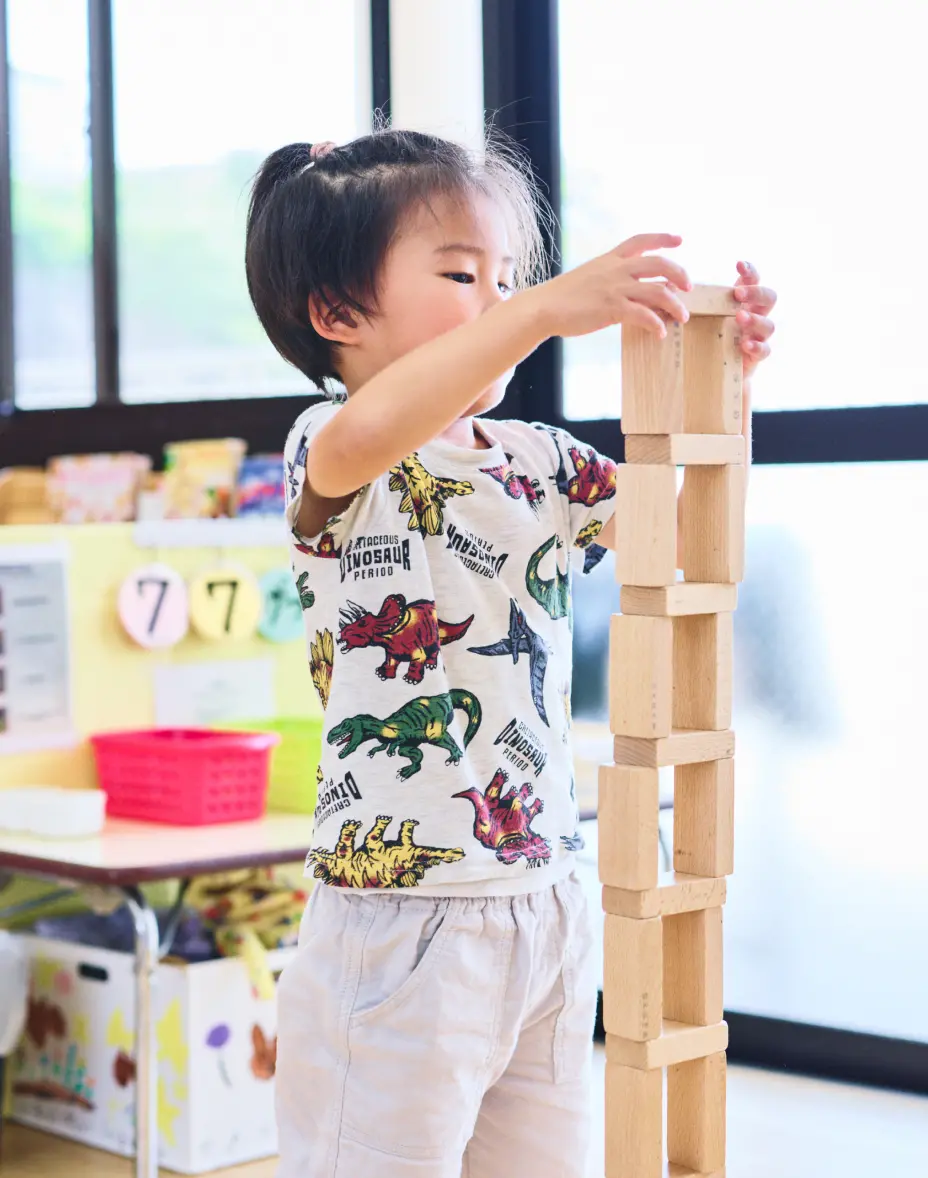 幼児が集中して積み木を高く積み上げている様子